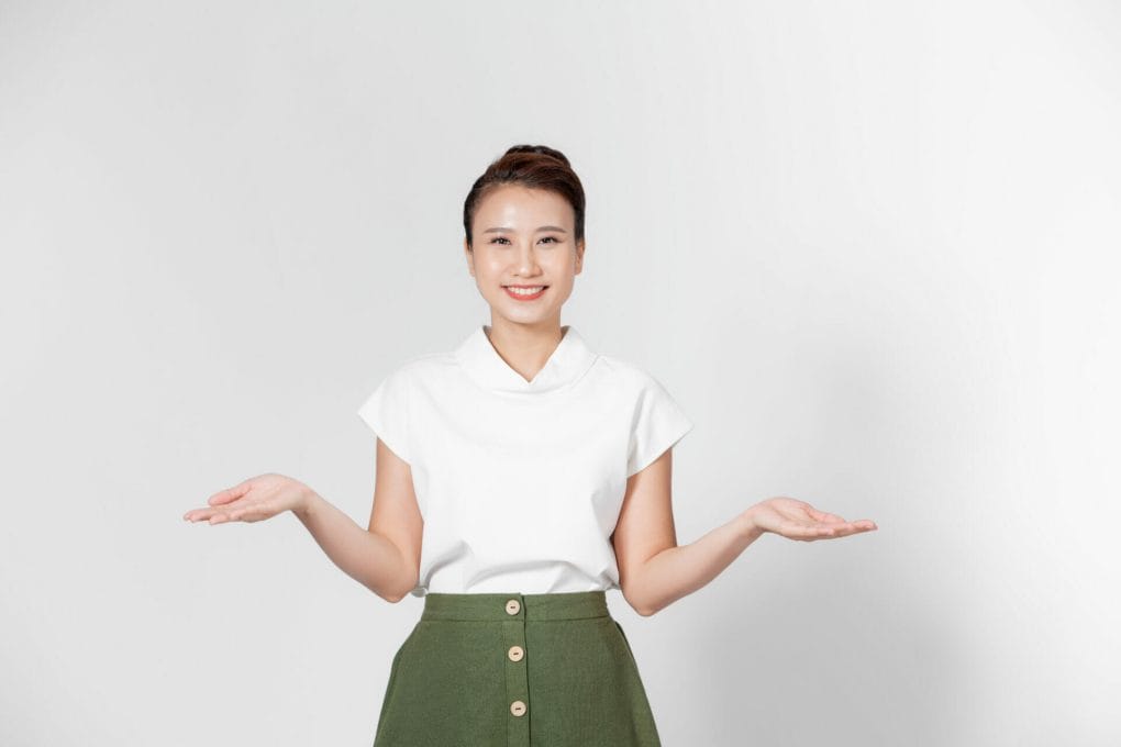 young asian woman raised her left right hand compare demonstrate product copy space